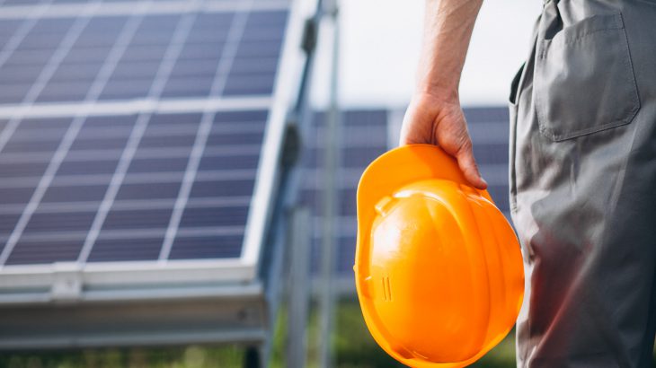 Man worker in the firld by the solar panels